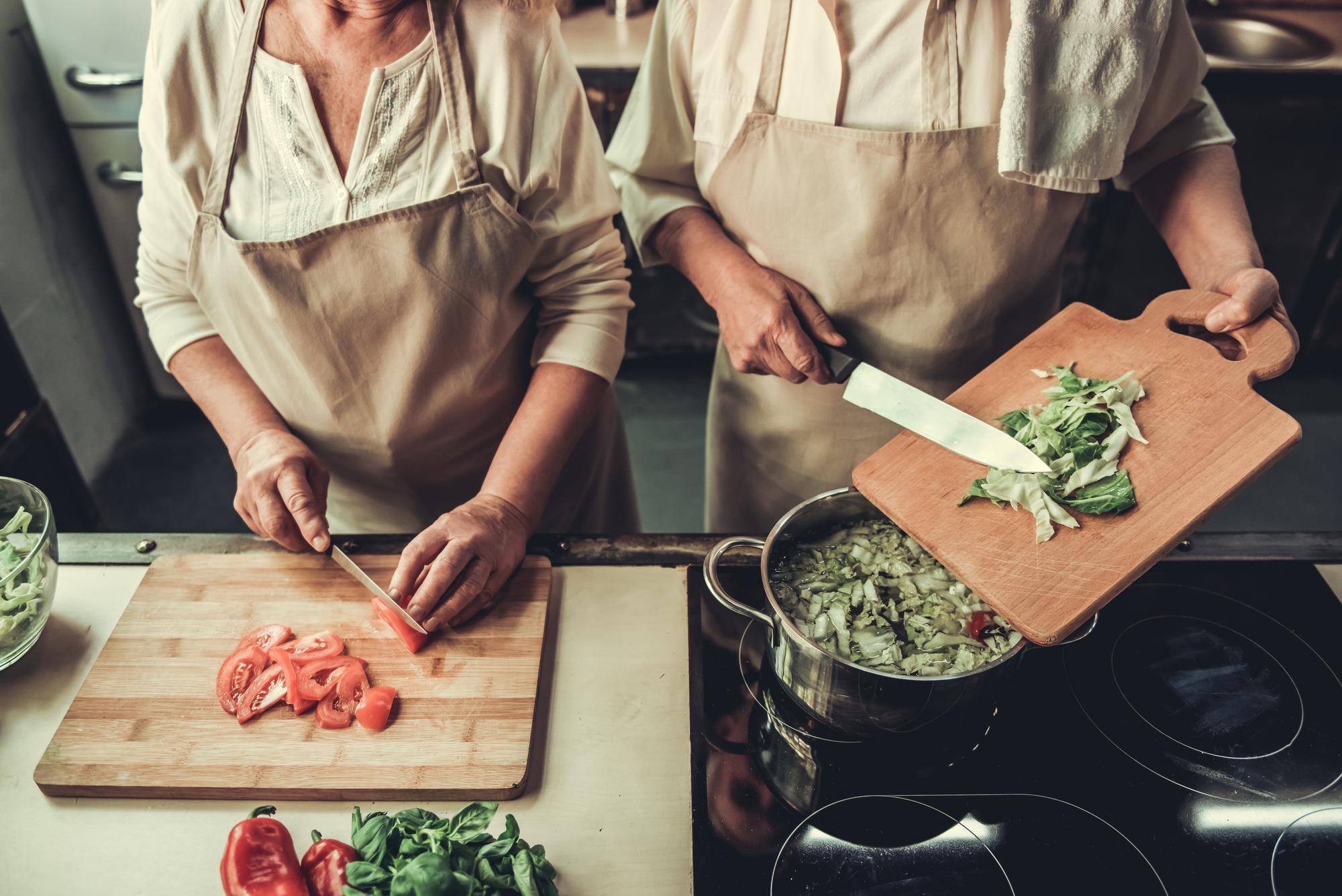 Two chefs preparing ingredients in rustic kitchen