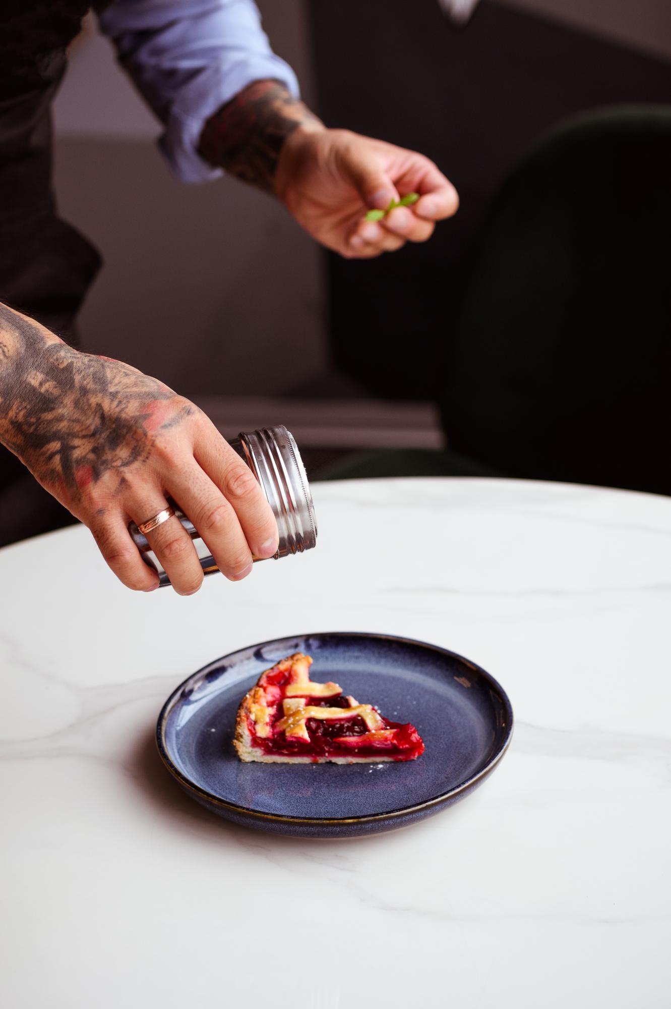 Chef arranging plated dish on dark table